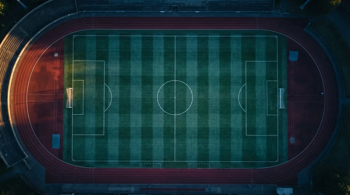 Ein Fussballplatz von oben gesehen, die Linien bilden ein helles Muster auf dem Rasen, Drohnenperspektive in der Morgendämmerung.